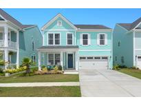 Two-story light teal house with white garage door and landscaping at 1016 Swamp Harrier Ave, Ravenel, SC 29470