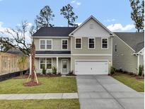Two-story house with gray siding, white garage door, and landscaped lawn at 2018 Quiet Ibis Rd, Hanahan, SC 29410