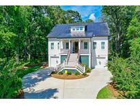 Two-story home with metal roof, green accents, and a circular driveway at 4858 Marshwood Dr, Hollywood, SC 29449
