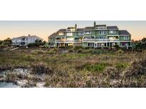 Green three-story building with multiple balconies overlooking grassy dunes at 7000 Palmetto Dr # 12E, Isle of Palms, SC 29451