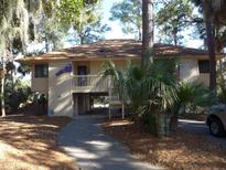 Elevated home with screened porch, walkway, and mature trees at 845 Club Cottage Rd, Edisto Island, SC 29438