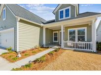 Green house with white trim, a front porch, and landscaped yard at 1104 Cooper Point St, Summerville, SC 29485