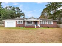 Brick ranch house with a white porch, attached garage, and well-maintained lawn at 127 Roberts Rd, Summerville, SC 29483