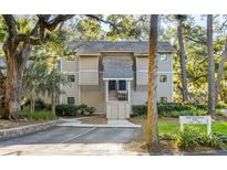 Exterior view of a tan colored building with grey trim, walkway, and landscaping at 162 High Hammock Villas, Seabrook Island, SC 29455