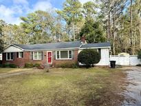 Brick ranch house with red door, landscaped lawn, and a white picket fence at 201 Center St, Walterboro, SC 29488