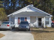 White one-story house with gray roof, two cars parked in driveway, and small front yard at 220 Two Pond Loop, Ladson, SC 29456