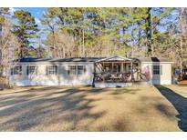 Tan mobile home with covered porch, American flag, and spacious yard at 250 W Medina St, Summerville, SC 29483