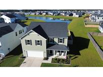 Two-story house with a gray roof and white garage, situated on a landscaped lawn near a pond at 268 Lucca Dr, Summerville, SC 29486