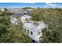 White two-story home with rooftop deck and outdoor seating at 79 Sandbar Ln, Folly Beach, SC 29439