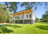 White modern home with large deck, grassy yard, and covered porch at 1782 Old Military Rd Rd, Charleston, SC 29412