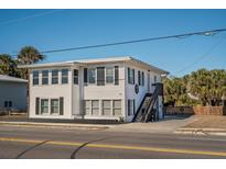Two-story beach house with white siding, black shutters, and a coral door at 405 Palmetto Blvd, Edisto Island, SC 29438