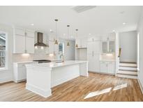 Modern white kitchen with island, stainless steel appliances, and hardwood floors at 4430 Beaver St, North Charleston, SC 29405