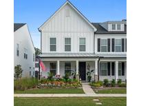 Two-story white farmhouse-style home with a front porch and landscaped yard at 1011 Swamp Harrier Ave, Ravenel, SC 29470