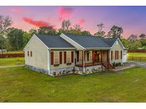 Beige house with brown shutters, a front porch, and landscaped yard at 150 Lisenby Dr, Moncks Corner, SC 29461