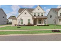Two-story farmhouse-style home with a front porch and landscaped lawn at 2040 Parish House Cir, Johns Island, SC 29455
