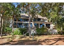Back of house with large windows and deck, surrounded by lush trees at 2942 Seabrook Island Rd, Seabrook Island, SC 29455