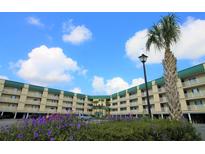 Two-story building with balconies, lush landscaping, and ample parking at 3701 Dock Site Rd # 205, Edisto Beach, SC 29438