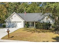 House exterior featuring a two-car garage, manicured lawn, and mature trees at 5382 Westchester Pl, North Charleston, SC 29418
