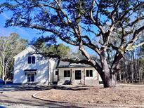 Two-story white farmhouse with a large oak tree and brick walkway at 3874 Srevir Rd, Johns Island, SC 29455