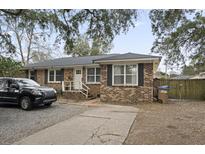 Brick ranch home with driveway, landscaping, and fenced backyard at 868 Dills Bluff Rd, Charleston, SC 29412