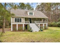 Two-story house with wraparound porch and stairs leading to the front entrance at 1575 Tacky Point Rd, Wadmalaw Island, SC 29487