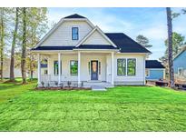 White farmhouse-style home with black roof, front porch, and landscaped lawn at 2837 Auldreeke Rd, Johns Island, SC 29455