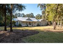 Gray farmhouse with metal roof, large porch, and landscaped yard at 3365 Westphal Dr, Johns Island, SC 29455