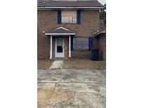 Brick townhouse with boarded windows and a small front yard at 7734 Suzanne Dr, North Charleston, SC 29418
