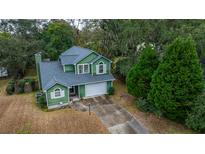 Aerial view of charming green house with driveway, surrounded by lush trees at 2336 Parkstone Dr, Charleston, SC 29414