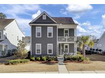 Two-story gray house with white accents, front porch, and landscaped yard at 703 N Hickory St, Summerville, SC 29483