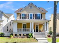 Two-story yellow house with white columns, porch, and landscaping at 114 Etiwan Park St, Daniel Island, SC 29492
