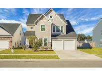 Two-story house with beige siding, a two-car garage, and landscaped front yard at 149 Cypress Preserve Blvd, Moncks Corner, SC 29461