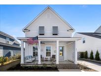 White two-story house with a front porch, rocking chairs, and American flag at 371 Ripple Park Dr, Summerville, SC 29486