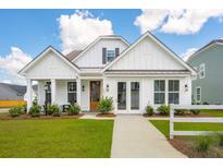 White farmhouse exterior with a brown door, landscaping, and walkway at 780 Opal Wing St, Moncks Corner, SC 29461
