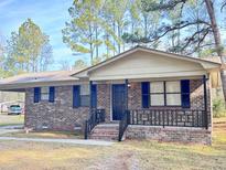 Brick ranch house with a covered porch, dark shutters, and a landscaped yard at 1401 Rivers St, Walterboro, SC 29488