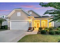 Tan house with white garage door, landscaping, and a covered porch at 459 Eastern Isle Ave, Summerville, SC 29486