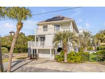 Two-story house with solar panels, balconies, and a detached garage, surrounded by palm trees at 109 Carolina Blvd, Isle of Palms, SC 29451