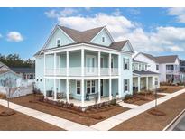 Two-story light teal house with white accents, front porch, and landscaped yard at 229 Symphony Ave, Summerville, SC 29486