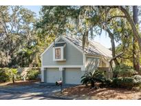 Gray two-car garage with a dormer window, nestled amongst lush greenery at 1019 Embassy Row Way, Seabrook Island, SC 29455