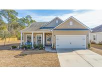 Beige house with white garage door, landscaping, and porch at 2028 Elvington Rd, Johns Island, SC 29455