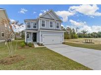 Two-story home with gray siding, attached garage, and landscaped lawn at 323 Abercom Place Dr, Moncks Corner, SC 29461
