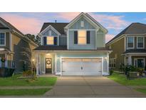 Charming two-story house with a light blue exterior, white garage door, and manicured lawn at 563 Alderly Dr, Moncks Corner, SC 29461