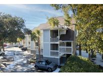 Gray two-story condo building with parking and mature trees at 208 Little Oak Dr, Folly Beach, SC 29439