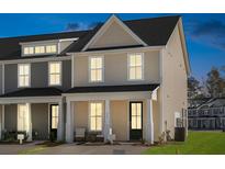 Two-story tan home with a covered porch and a black front door, at dusk at 219 Abercom Place Dr, Moncks Corner, SC 29461