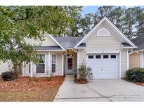 Charming yellow house with a white garage door and landscaping at 4845 Carnoustie Ct, Summerville, SC 29485