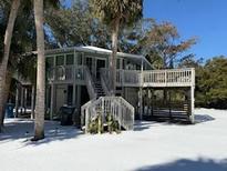 Elevated two-story home with wrap-around decks, stairs, and fenced yard at 613 Pompano St, Edisto Island, SC 29438
