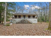 House exterior featuring a wrap-around porch and wooded setting at 6310 Shilelagh Oaks Pkwy, Ravenel, SC 29470