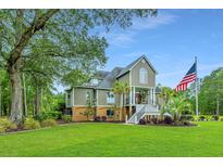 Two story home with a large front yard, palm trees, and American flag at 975 Mayfield St, Summerville, SC 29485