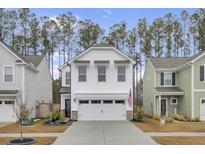 Two-story white house with a two-car garage and landscaping at 155 Surfbird Rd, Summerville, SC 29486