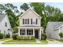 Tan two-story house with black shutters, a front porch, and landscaping at 1762 Bee Balm Rd, Johns Island, SC 29455